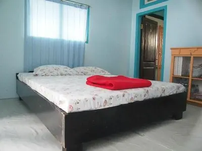 a bed with a red blanket on top of it at Sparsha rooms in Kaniyāmbetta