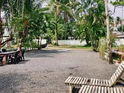 a park with a bench and tables and palm trees at Bamboo villa in Cochin