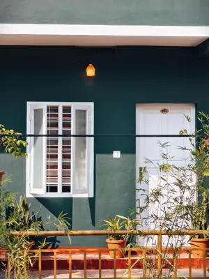 a green house with a white door and window at Bamboo villa in Cochin