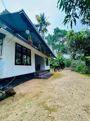 a white house with a blue roof and a yard at Parathanathu Homestay in Viripara