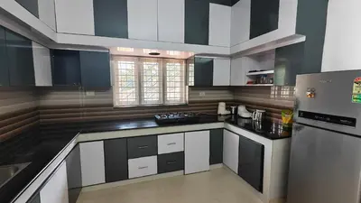 a kitchen with black and white cabinets and a refrigerator at Havenza Homestayz in Athirappilly