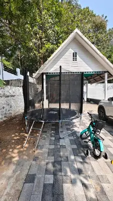 a batting cage and a scooter parked in front of a house at Havenza Homestayz in Athirappilly