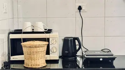 a kitchen counter with a microwave and a basket at BOHO Living Kochi Airport in Ernakulam