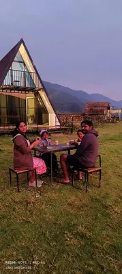 a group of people sitting at a picnic table in a field at Misty Colina in Kottakamboor