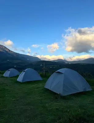 three tents in a field with mountains in the background at Misty Colina in Kottakamboor