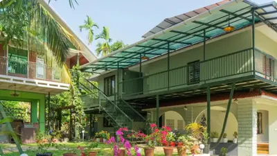 a building with a balcony and flowers in a yard at NEST nature homestay in Kalpetta