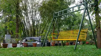 a yellow swing in a park with a car in the background at NEST nature homestay in Kalpetta