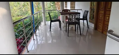 a dining room with a table and chairs on a balcony at The Trio in Kalpetta
