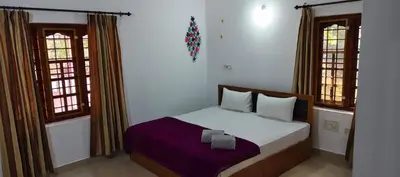 a bedroom with a bed and two windows at The Trio in Kalpetta