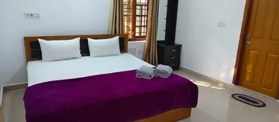 a bedroom with a bed with two towels on it at The Trio in Kalpetta