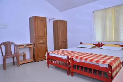 a bedroom with a bed and a desk and a chair at Lead Homestay Chalakudy in Kizhake Chālakudi