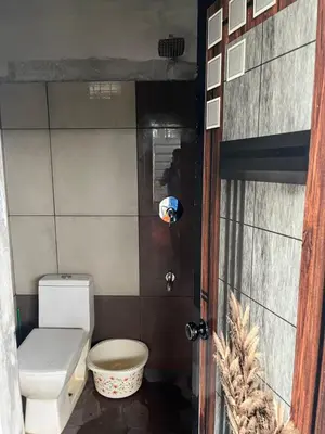 a small bathroom with a toilet and a door at Tulips villa in Mānantoddy