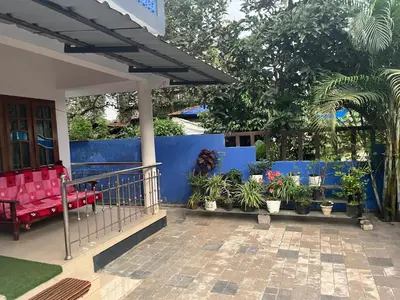 a porch of a house with red chairs and plants at Tulips villa in Mānantoddy