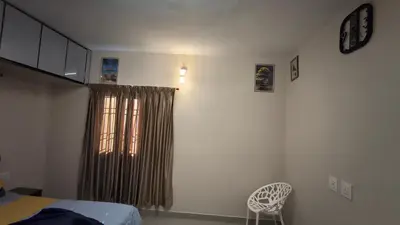 a bedroom with a bed and a window and a chair at Hideout luxe in Ooty