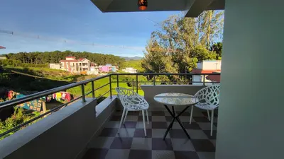 a balcony with a table and chairs and a view at Hideout luxe in Ooty