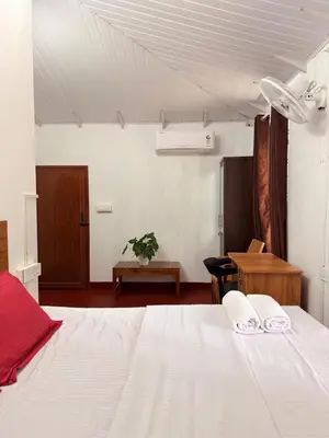 a bedroom with a white bed and a table at Avocado Orchards - Villa in Kenichira