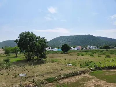 a field with trees and a town in the distance at Happy Holidays Cottage in Wodapatti