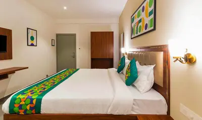 a bedroom with a large white bed with green pillows at Treebo Global Orchid in Mysore