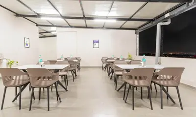 a room with tables and chairs and a chalkboard at Treebo Global Orchid in Mysore