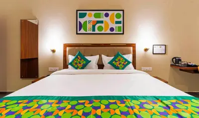 a bedroom with a large white bed with colorful pillows at Treebo Global Orchid in Mysore