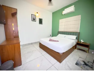 a bedroom with a white bed and a green wall at Tokyoz Inn Calicut in Kunnamangalam