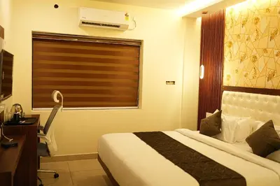 a bedroom with a bed and a desk and a window at Elite Group Mysore in Mysore