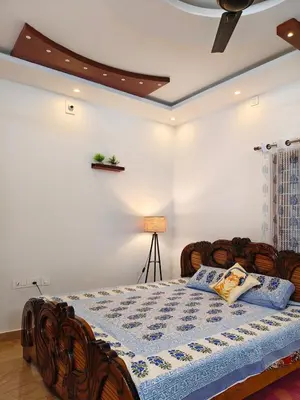 a bedroom with a bed with a blue quilt on it at Hridayam Hill view nest in Marayoor