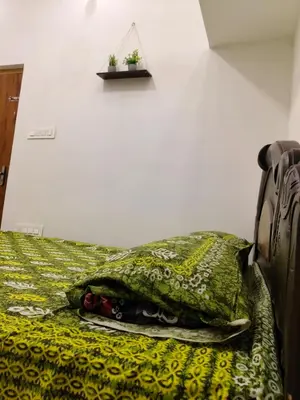 a bed with a green blanket and two plants on it at Hridayam Hill view nest in Marayoor