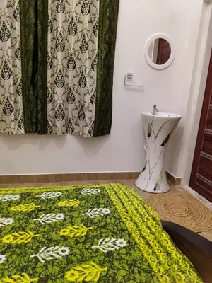 a bathroom with a green shower curtain and a toilet at Hridayam Hill view nest in Marayoor