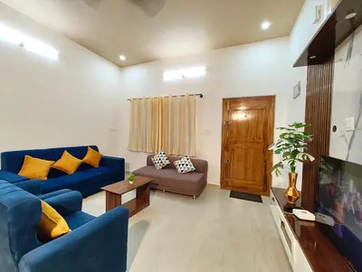 a living room with a blue couch and a tv at Namasv 2BHK AC House in Narasimharaja Puram