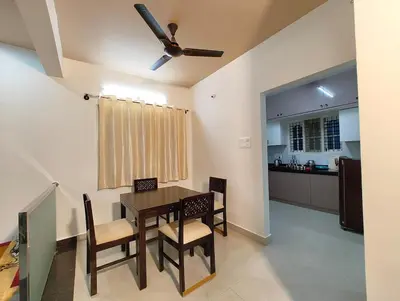 a dining room with a table and chairs and a kitchen at Namasv 2BHK AC House in Narasimharaja Puram