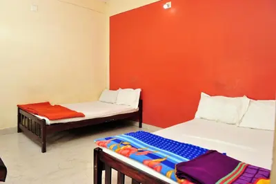 a room with two beds and a red wall at Alfa Tourist Home, Batheri in Sultan Bathery