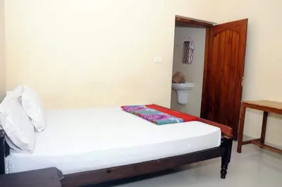 a bedroom with a bed and a toilet in it at Alfa Tourist Home, Batheri in Sultan Bathery