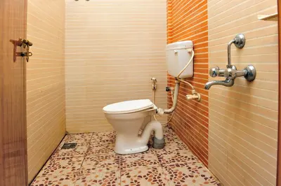 a bathroom with a toilet in a tiled room at Alfa Tourist Home, Batheri in Sultan Bathery