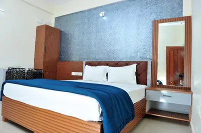 a bedroom with a large bed with a blue wall at Alfa Tourist Home, Batheri in Sultan Bathery
