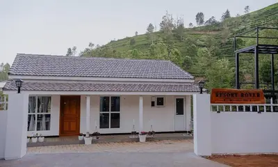 a small white house with a sign in front of it at Prithivee Homestay in Kotagiri