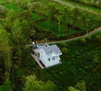 an overhead view of a white house in the forest at Prithivee Homestay in Kotagiri