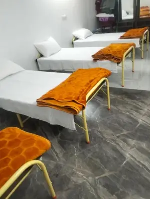 a row of beds with orange blankets on them at Prithivee Homestay in Kotagiri