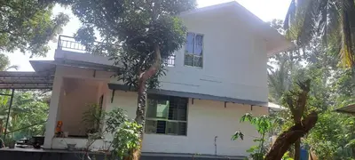 a white house with a tree in front of it at Sthala Organic Farm Stay in Nallepilli