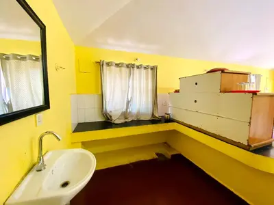 a yellow bathroom with a sink and a mirror at Skyline Haven cottage ll in Ooty