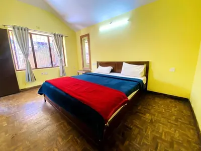 a bedroom with a large bed in a yellow room at Skyline Haven cottage ll in Ooty