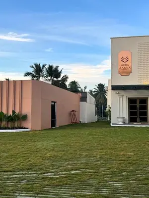 a building with a large grass field in front of it at Hotel Aarka in Mettuppālaiyam