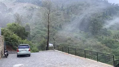 a car parked in a parking lot in front of a mountain at The Brook by Turquoise Villas in Kodaikānāl