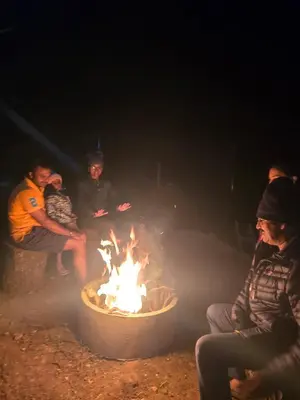 a group of people sitting around a fire at The Brook by Turquoise Villas in Kodaikānāl