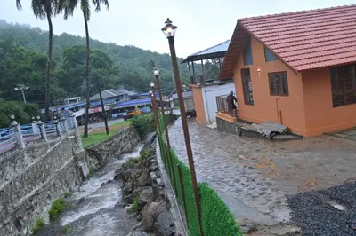 a house with a fence next to a river at Mystic Rock Staycations in Mannārakkāt