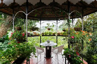 a patio with a table and chairs in a garden at SaffronStays Oakridge Cottage in Coonoor