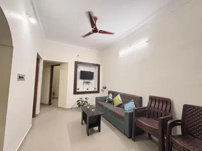 a living room with a couch and a ceiling fan at Kamadhenu Homestay, Comapact 2BHK OPP Mysore zoo B in Mysore