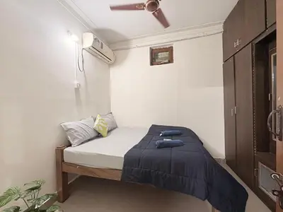 a small bedroom with a bed with a blue blanket at Kamadhenu Homestay, Comapact 2BHK OPP Mysore zoo B in Mysore