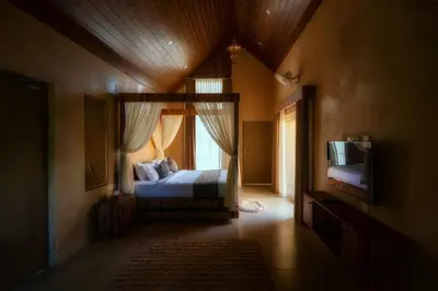 a bedroom with a bed and a window and a television at Golf Valley Luxury Resort Wayanad in Vythiri