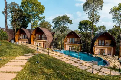 a row of houses with a swimming pool in front at Golf Valley Luxury Resort Wayanad in Vythiri